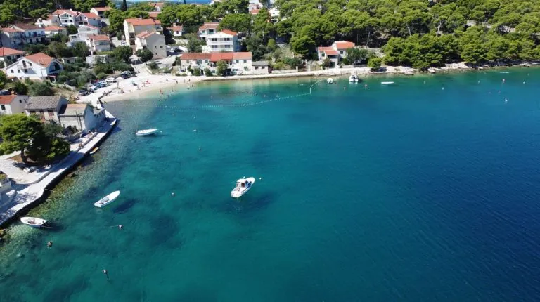 Blick auf eine Bucht mit türkisblauem Meer und Küstenort in Kroatien.